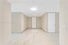 Large-format light-toned tile flooring, neutral wall palette, flat-panel doors with metallic hardware, and flush-mount ceiling lighting