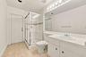 This well-appointed full bathroom features a spacious vanity, large mirror, glass-enclosed shower, and convenient access from the main living areas an