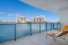 Covered balcony featuring stone flooring and a glass-paneled railing overlooking the water