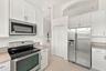 The kitchen features crisp white cabinetry, stainless steel appliances, ample storage, and a functional layout designed for everyday convenience.