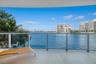 Covered balcony featuring stone flooring and a glass-paneled railing overlooking the water