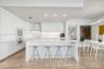 Modern kitchen featuring white flat-panel cabinetry, a central island with a solid-surface countertop, built-in double ovens, and polished stone floor