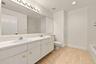 This well-appointed upstairs bathroom features an expansive dual-sink vanity, generous counter space, abundant cabinetry, and a large mirror with over