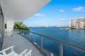 Curved balcony featuring light-toned tile flooring and a glass-panel railing with metal frame