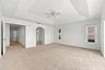 An impressive primary bedroom featuring a decorative tray ceiling, generous proportions, and a private entrance to the adjoining bathroom and dressing