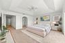 An impressive primary bedroom featuring a decorative tray ceiling, generous proportions, and a private entrance to the adjoining bathroom and dressing