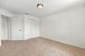 This inviting fourth bedroom features plush carpeting, neutral finishes, decorative crown molding, and a generous layout offering plenty of flexibilit