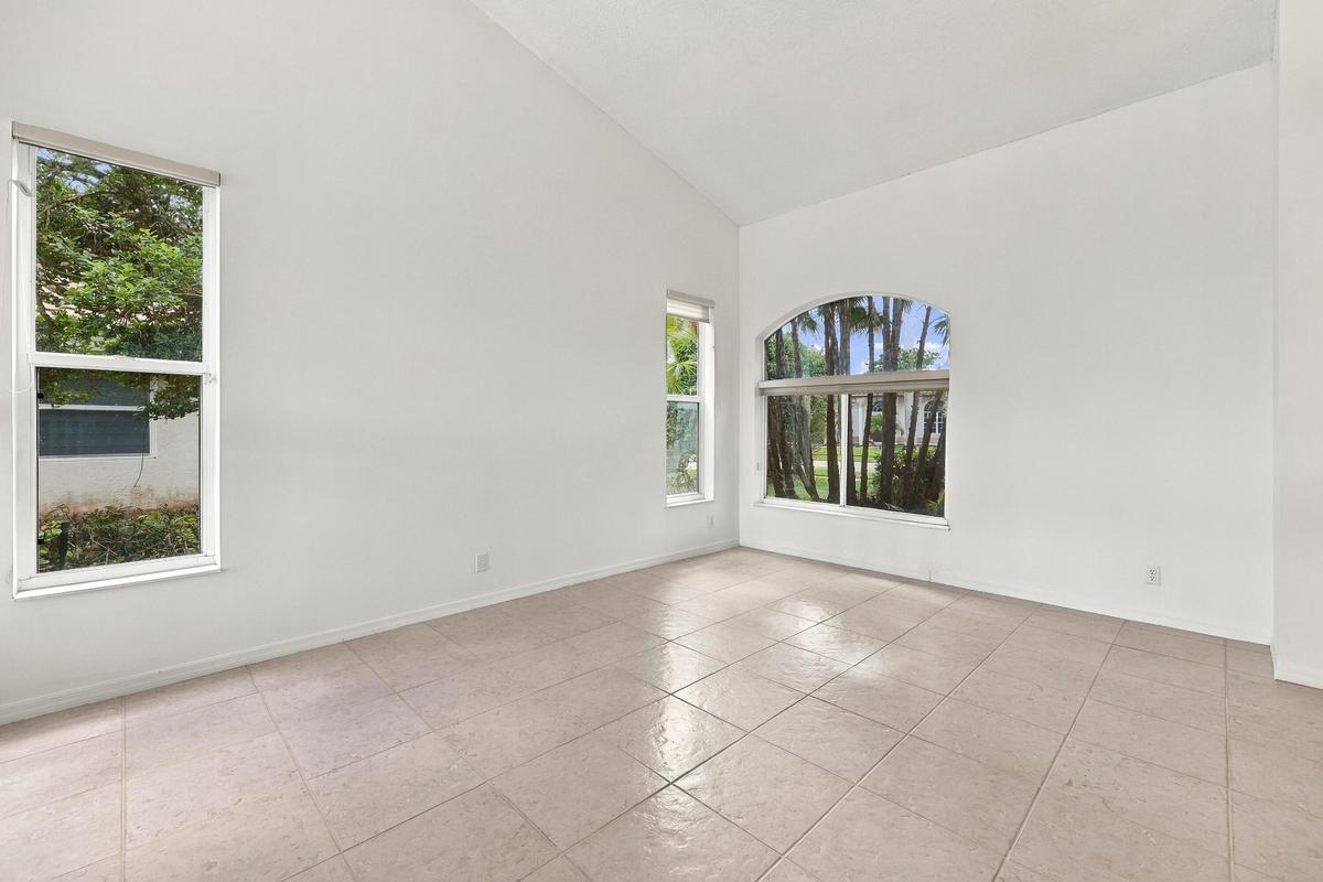 Soaring vaulted ceilings, expansive windows, and abundant natural light create a bright, inviting formal living room with an impressive sense of space