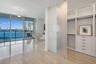 Floor-to-ceiling glass wall with sliding doors, polished stone tile flooring, frosted glass privacy panel, custom built-in wardrobe with soft-close dr