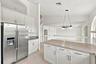 The kitchen features crisp white cabinetry, stainless steel appliances, ample storage, and a functional layout designed for everyday convenience.