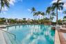 Experience resort-style living at the beautiful community swimming pool, surrounded by swaying palms, expansive lounging areas, and the impressive Boc