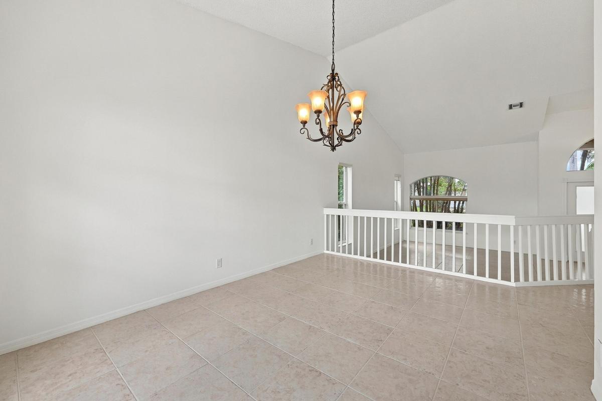 A decorative chandelier, dramatic arched window, and vaulted ceilings provide an elegant setting for both intimate dinners and larger celebrations.