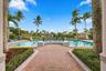 Experience resort-style living at the beautiful community swimming pool, surrounded by swaying palms, expansive lounging areas, and the impressive Boc
