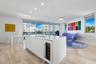 Kitchen island featuring a solid-surface countertop, built-in wine refrigerator, undermount sink, and minimalist cabinetry, complemented by stone-fini