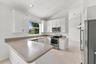 A thoughtfully arranged kitchen offering extensive counter space, white cabinetry, stainless steel appliances, and convenient access to the adjoining 