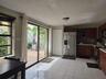 Kitchen featuring dark wood cabinetry, stainless steel appliances, tiled flooring, and sliding glass doors leading to a paved patio