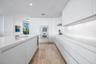 Minimalist kitchen featuring flat-panel cabinetry, white stone-surface countertops, built-in wall ovens, stone-finish flooring, and recessed ceiling l