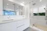 Floating dual-sink vanity with a solid surface countertop, large wall-to-wall mirror, glass-enclosed walk-in shower, built-in soaking tub, and recesse