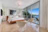Polished stone flooring, floor-to-ceiling glass sliding doors, private balcony, three-blade ceiling fan, and plantation shutters