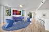 Open-concept interior featuring natural stone flooring, flush-mount circular lighting, expansive windows, and built-in minimalist cabinetry with integ