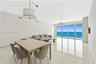 Floor-to-ceiling glass panel windows, polished tile flooring, pendant lighting fixtures, and an exterior balcony