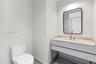 Modern vanity featuring a stone-finish countertop, integrated sink, metal-frame base, rounded rectangular mirror, and brushed-finish faucet