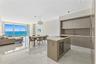Open-concept interior featuring light-toned flooring, high-gloss flat-panel cabinetry, a stone-topped kitchen island with a built-in wine cooler, rece