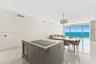 Open-concept interior featuring large-format stone-look flooring, center island with stone countertop and built-in wine refrigeration, dual drum penda
