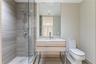 Modern bathroom featuring a wood-finish floating vanity with a light stone countertop, a glass-enclosed shower with horizontal-patterned wall tile, an