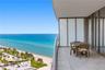 Private balcony featuring expansive stone-tile flooring, floor-to-ceiling glass panel sliding doors, and frosted glass privacy partitions