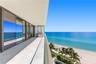 Expansive balcony featuring large-format tile flooring, a glass panel railing, built-in stainless steel outdoor kitchen equipment, and full-height sli