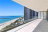 Private balcony featuring light-toned tile flooring, a glass panel railing, and a covered ceiling