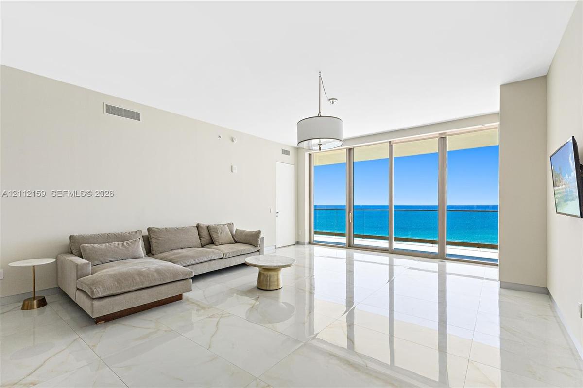 Polished stone flooring, floor-to-ceiling glass sliding doors, private balcony, and pendant lighting