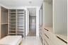Walk-in closet featuring extensive built-in cabinetry, floor-to-ceiling shelving, recessed drawer units, and polished stone-finish flooring