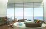Floor-to-ceiling windows featuring ocean scenery, curved architectural wall, built-in wooden desk, and wood-finish flooring