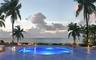 Circular pool featuring a stone-tiled deck, surrounded by mature palm trees and coastal scenery