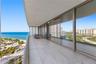 Expansive covered balcony featuring large-format tile flooring, floor-to-ceiling glass paneling, and metallic framing
