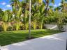 Private backyard featuring a paved stone patio, manicured lawn, established perimeter landscaping, and a decorative concrete masonry wall