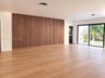 Expansive interior featuring wood-finish flooring, a floor-to-ceiling vertical wood slat accent wall, recessed lighting, and large sliding glass doors