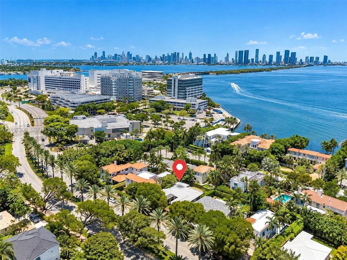 Aerial perspective featuring mature coastal landscaping, proximity to the bay, and a cityscape backdrop