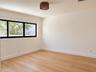 Neutral-toned interior featuring wood-finish flooring, a black-frame rectangular window, and a woven-textured flush-mount ceiling light