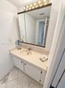 Vanity featuring a solid surface countertop with an integrated sink, three-panel medicine cabinet, five-bulb light fixture, and stone-finish tile floo