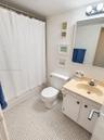 Bathroom featuring a vanity with integrated sink, rectangular wall-mounted mirror, two-light fixture, and tiled flooring