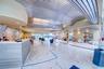 Spacious interior featuring a metallic corrugated ceiling, polished stone flooring, a large reception desk with wood-finish paneling, and an accent wa