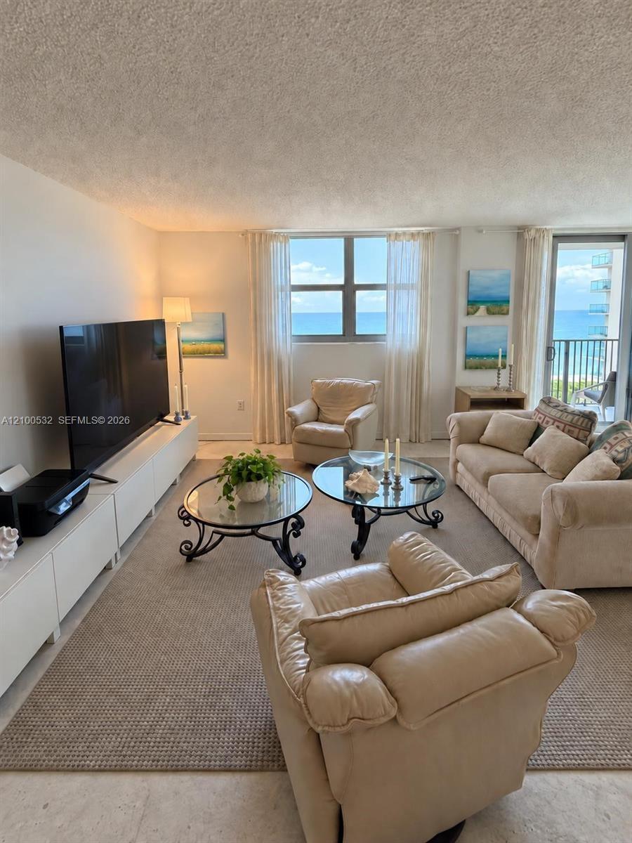 Living area featuring large windows, integrated storage cabinetry, neutral wall-to-wall carpeting, and a glass sliding door providing access to a balc