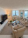 Living area featuring large windows, integrated storage cabinetry, neutral wall-to-wall carpeting, and a glass sliding door providing access to a balc