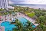 Outdoor swimming area featuring multiple pools, a water slide, expansive paved deck, and mature palm trees