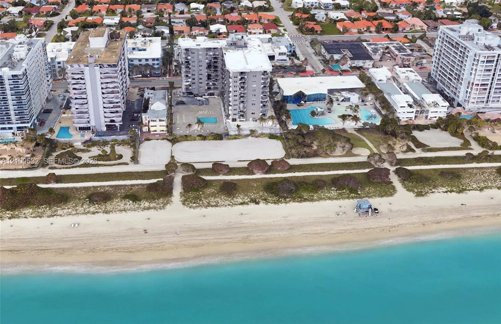 Aerial perspective of beachfront high-rise properties featuring direct access to sandy coastline, paved recreational paths, and swimming pools