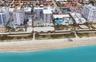 Aerial perspective of beachfront high-rise properties featuring direct access to sandy coastline, paved recreational paths, and swimming pools