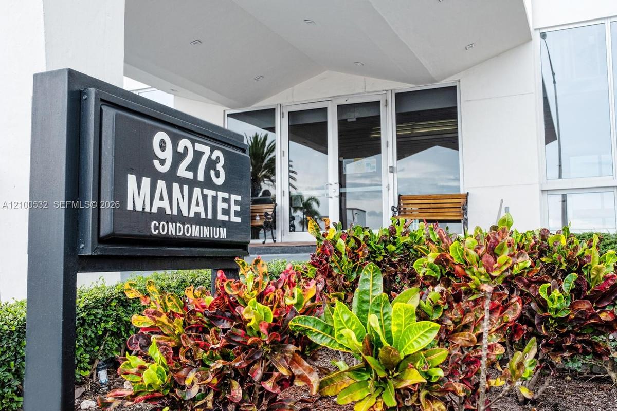 Building exterior featuring multi-pane glass entry doors, expansive windows, and manicured tropical landscaping